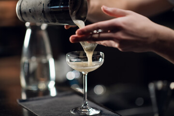 An experienced bartender prepares an alcoholic cocktail. No face, close-up, copy space