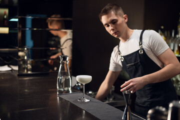 the young bartender prepared a milk cocktail and put it on the bar.