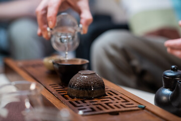 Special yixing clay cups for chinese tea are prepared for the ceremony on the gongfu bamboo tray. Close-up with blurred background