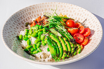 Hawaiian salmon fish poke bowl with rice, edamame, mango, cherry tomatoes, avocado, sesame seeds and seaweeds. Buddha bowl. Diet food