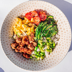 Hawaiian chicken poke bowl with rice, edamame, mango, cherry tomatoes, avocado, sesame seeds and seaweeds. Buddha bowl. Diet food