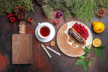 top view tasty choco eclairs with red berries and tea on dark background pie cake dessert sweet