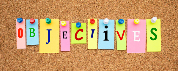 Color notes with letters pinned on a cork board. Word OBJECTIVES.