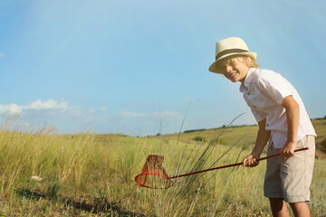 Cute little boy with butterfly net outdoors, space for text. Child spending time in nature