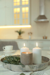 Fototapeta na wymiar Beautiful eucalyptus branches, flowers and burning candles on napkin in kitchen, space for text. Interior element