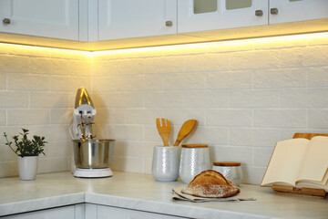 Countertop with modern food processor, cookbook and fresh bread in stylish kitchen