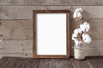 Rough wooden frame and a branch of cotton on a wooden background