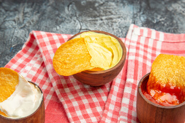 Delicious crispy potato chips ketchup mayonnaise sauce on red stripped towel on gray table