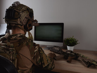 US Army special forces operator looking at the computer screen in the office. Seal team operator in...