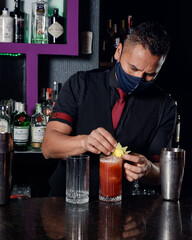 A young professional bartender prepares cocktails for his clients at work. profession concept