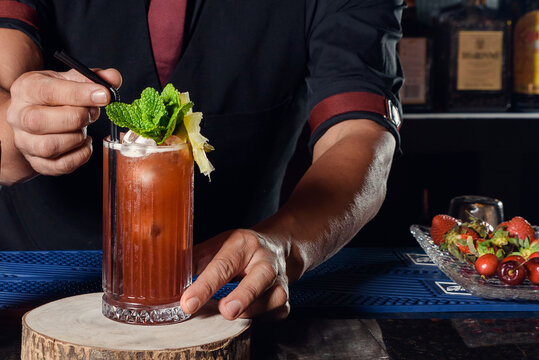 A young professional bartender prepares cocktails for his clients at work. profession concept