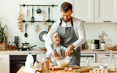 Happy man with kid preparing dough at home.