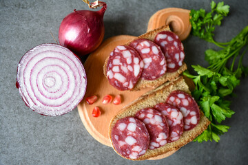 Snack sandwich black bread, salami sausage, fresh parsley, purple onion