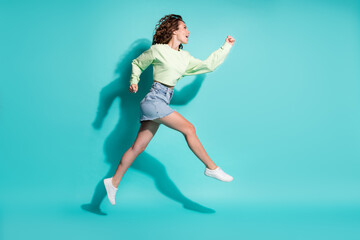 Full length body size side profile photo of beautiful girl jumping high running fast isolated on bright teal color background