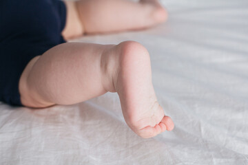 Feet of baby boy on bed. Legs on a white background.