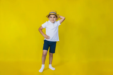 A little boy in a white shirt and straw hat on a yellow background.the concept of recreation and tourism.