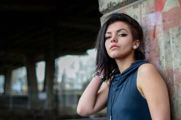 Fototapeta na wymiar Beautiful young brunette woman with blue tank top on a street urban background