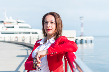 Obraz premium business woman in a red suit stands by the sea