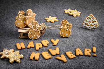 New year's ginger cookies. A cookie-wrapped happy new year greeting. Ginger cookies in the form of snowman in a winter sleigh. Grey background.