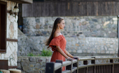 Beautiful young brunette woman with orange dress on a street urban background