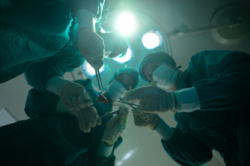 professional surgery team in the operating room, urgent surgery. Professional smart intelligent surgeons standing near the patient and performing an operation while saving his life