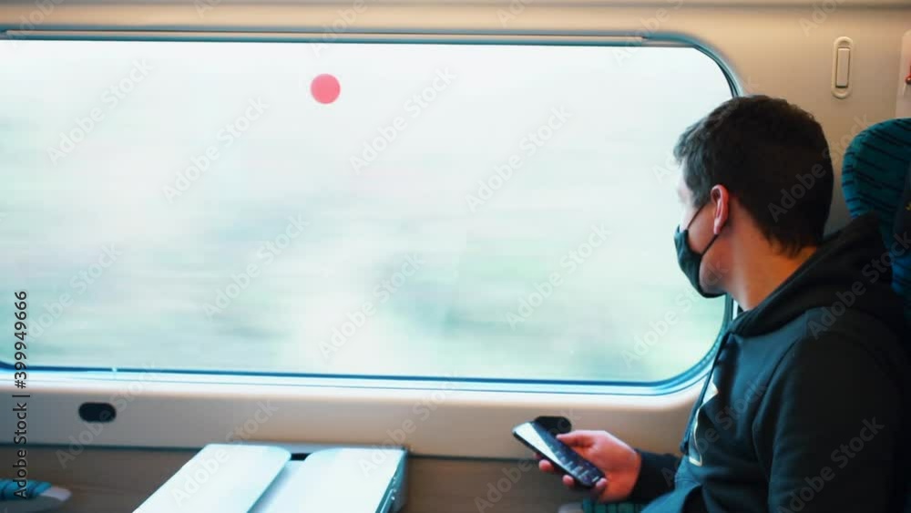 Poster a man uses a mobile phone in a train carriage near the window. hand holds a smartphone uses mobile i
