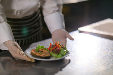 Asian Male chef presenting the dish in the kitchen. Selective focus.