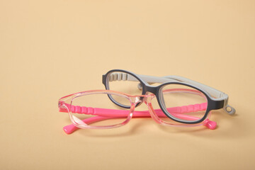 two pairs of children's glasses on a beige background