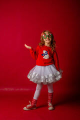 little girl in carnival glasses holds a gift on a red background, christmas