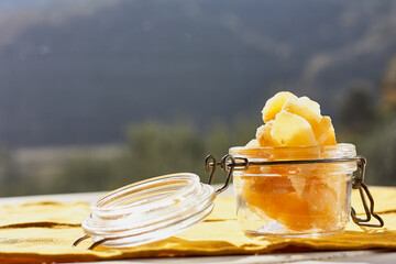 Candied ginger slices in a glass jar on the table in nature background. Dehydrated oriental fruits....