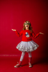 little girl in carnival glasses holds a gift on a red background, christmas. 