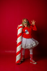 little girl on red background with big caramel, new year