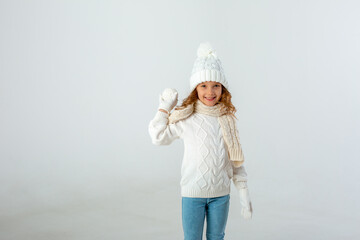 cute little girl dressed in a winter white hat and clothes holding a snowball on a white background
