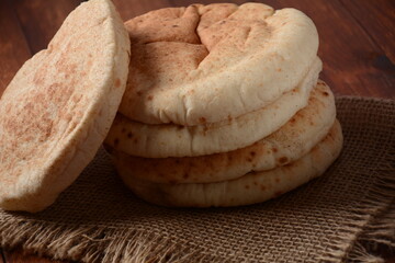 A stack of pita breads. Pita bread on wooden board, Arabic bread, soft baked flatbreads. Popular Israeli food
