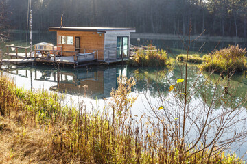 landing stage house on wooden pier in water in forest in evening