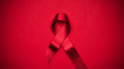 Infection symbol. Red ribbon symbol in hiv world day on dark red background. Awareness aids and cancer. Healthcare and medical concept. - obrazy, fototapety, plakaty