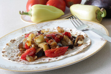 Vegetable dish, peppers, eggplant and tomatoes stewed in pita bread on a plate
