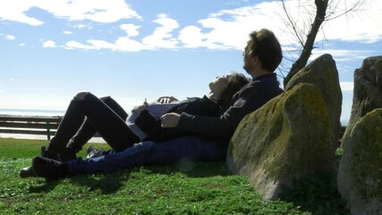 Pregnant woman enjoying freedom from isolation laying in park in front of the ocean - Powered by Adobe