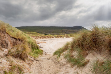 Sandy beach and dunes on West coast of Ireland. Selective focus.Cloudy sky © mark_gusev