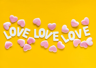 Valentine's Day yellow background with pink hearts and word Love lined with white wooden letters.Mother's Day, March 8 greeting card