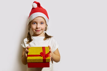 funny girl in a Santa claus hat opens a Christmas gift, portrait of a girl on a white background
