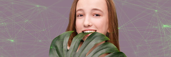 Young smiling girl with monstera leaf. Little model. Cosmetology health concept. Beautiful tropical leaf. Stomatology medical treatment. Female person happy portrait. Gery background. Copyspace
