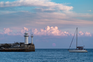 Obraz premium Yacht sails near the Yalta lighthouse