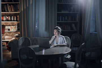 young woman works with computer in the evening at home