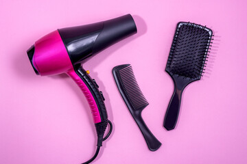 Hair dryer, Comb and hair brush on a pink background. Professional hairdresser set. Tools necessary...