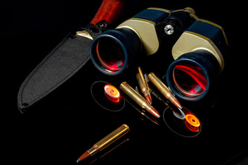 Military binoculars and cartridges on mirror background