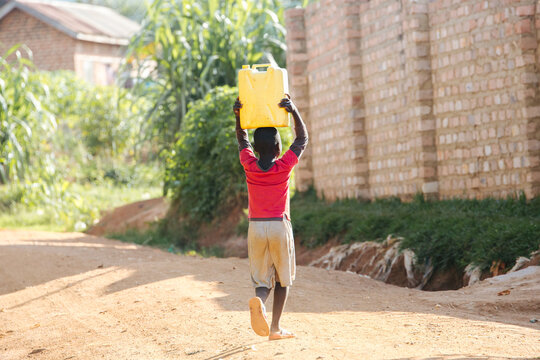 Child carrying water cans in Uganda, Africa