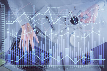 Multi exposure of man's hands typing over computer keyboard and forex graph hologram drawing. Top view. Financial markets concept.