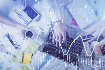 Multi exposure of man's hands typing over computer keyboard and forex graph hologram drawing. Top...
