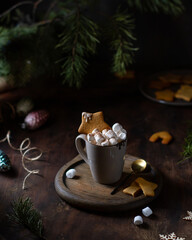 Hot chocolate with marshmallows in a mug on the table, a bouquet of fir branches, cookies, Christmas tree decorations.